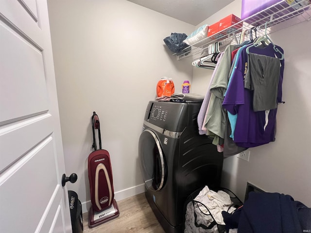 laundry room featuring laundry area, washer / clothes dryer, wood finished floors, and baseboards