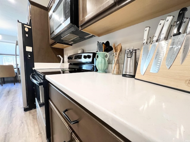 kitchen with stainless steel appliances, light countertops, light wood-style floors, and dark brown cabinets