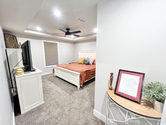 carpeted bedroom with ceiling fan, baseboards, visible vents, and a raised ceiling