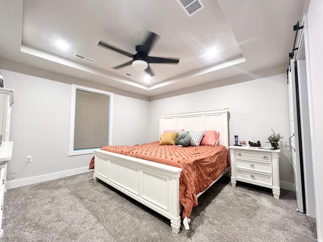 bedroom with a tray ceiling, visible vents, and carpet flooring