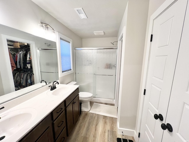 full bath featuring double vanity, wood finished floors, a sink, and a shower stall