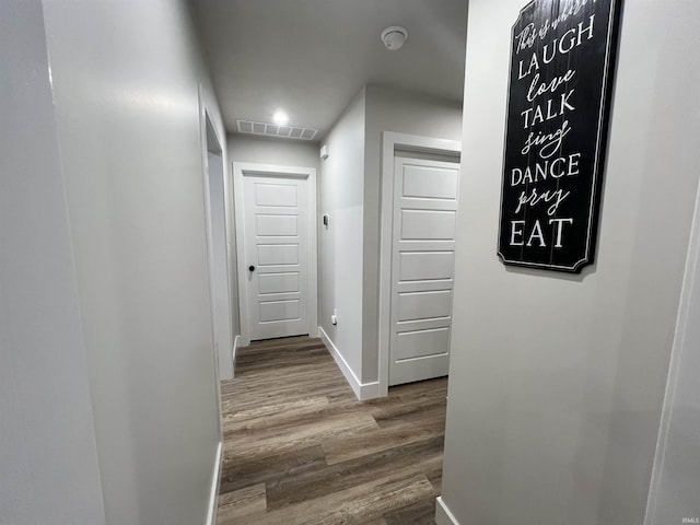 corridor featuring baseboards, visible vents, and wood finished floors