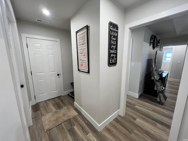 hallway with visible vents, baseboards, and wood finished floors