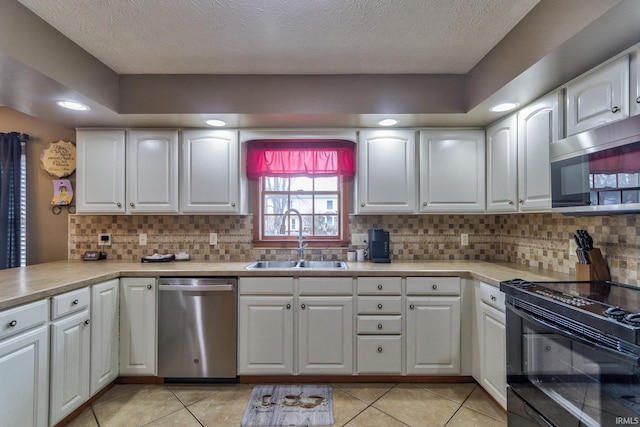 kitchen featuring appliances with stainless steel finishes, light countertops, white cabinets, and a sink