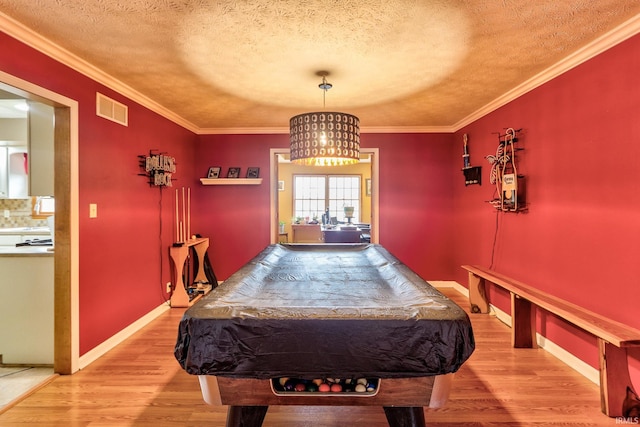 rec room featuring ornamental molding, light wood-type flooring, visible vents, and baseboards