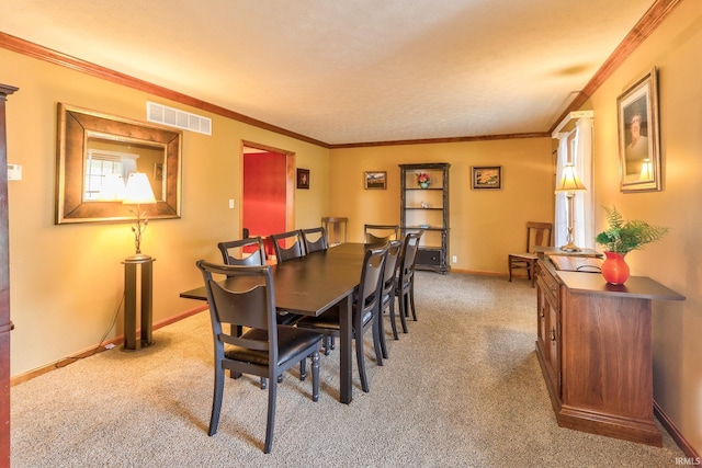 dining space featuring crown molding, baseboards, visible vents, and light colored carpet