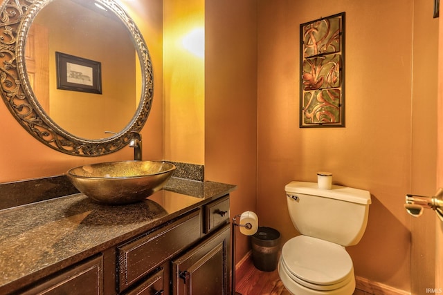 bathroom featuring toilet, baseboards, wood finished floors, and vanity