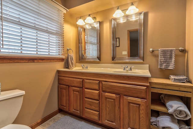 bathroom with double vanity, tile patterned flooring, a sink, and toilet