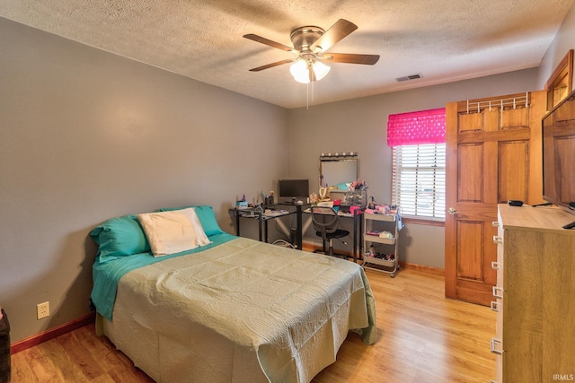 bedroom with light wood-type flooring, visible vents, baseboards, and a textured ceiling