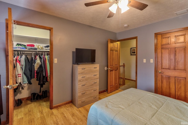 bedroom featuring visible vents, baseboards, a closet, light wood finished floors, and a walk in closet