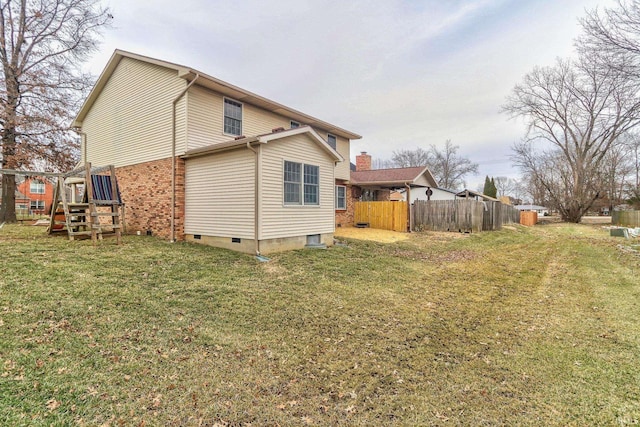 back of house featuring crawl space, brick siding, and a lawn