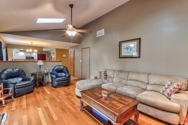 living room with vaulted ceiling with skylight, light wood-type flooring, visible vents, and an inviting chandelier