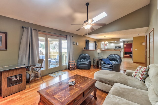 living room with light wood-style flooring, vaulted ceiling, and ceiling fan with notable chandelier