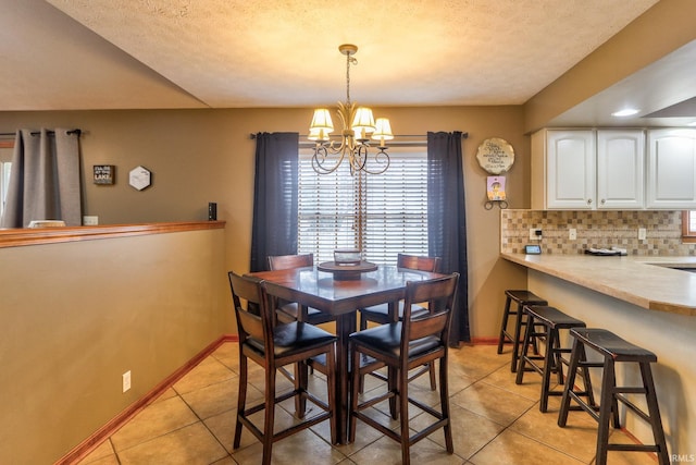 dining space with light tile patterned floors, a textured ceiling, baseboards, and a notable chandelier