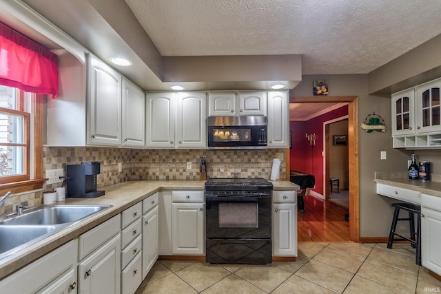 kitchen with glass insert cabinets, white cabinets, and black stove