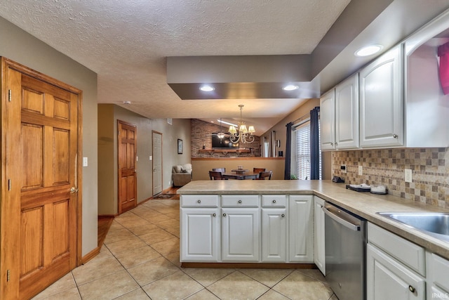 kitchen with decorative light fixtures, a peninsula, light countertops, white cabinetry, and stainless steel dishwasher