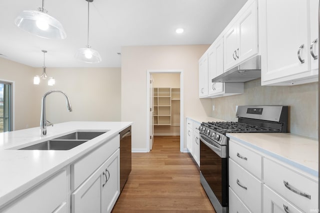 kitchen featuring under cabinet range hood, a sink, white cabinets, appliances with stainless steel finishes, and pendant lighting