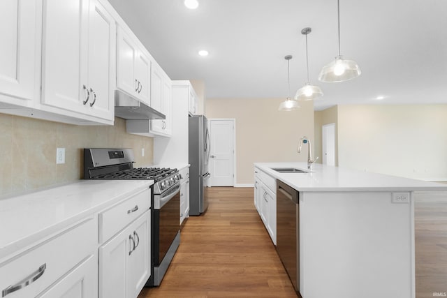 kitchen featuring a center island with sink, stainless steel appliances, light countertops, under cabinet range hood, and a sink