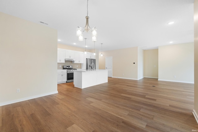 kitchen with stainless steel appliances, visible vents, white cabinets, open floor plan, and decorative light fixtures