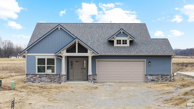 craftsman house featuring a garage, stone siding, and a shingled roof