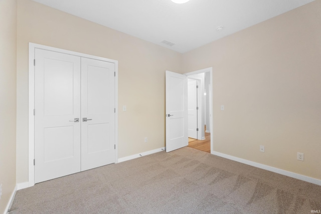 unfurnished bedroom featuring light carpet, baseboards, visible vents, and a closet