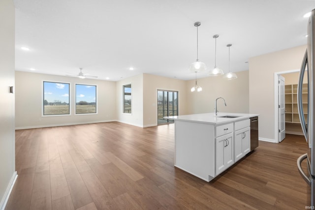 kitchen with a kitchen island with sink, a sink, open floor plan, light countertops, and dishwasher