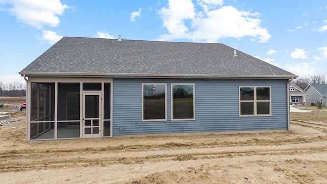 back of house featuring a sunroom and roof with shingles