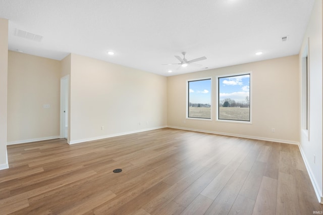 unfurnished room with light wood-style flooring, visible vents, and baseboards