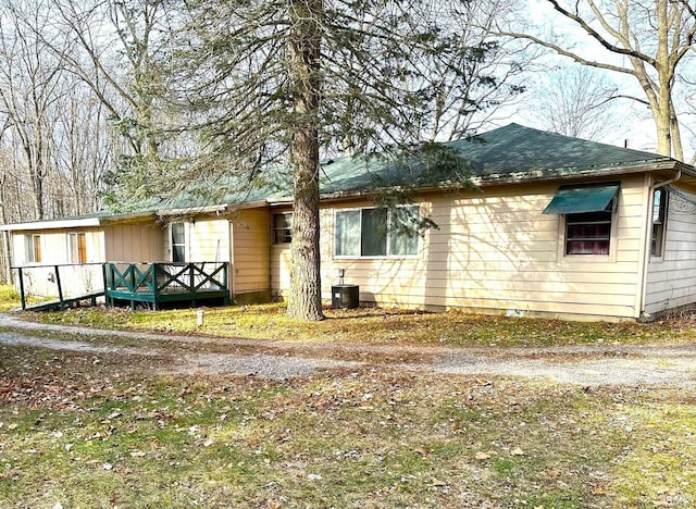 view of front of property featuring a shingled roof and cooling unit