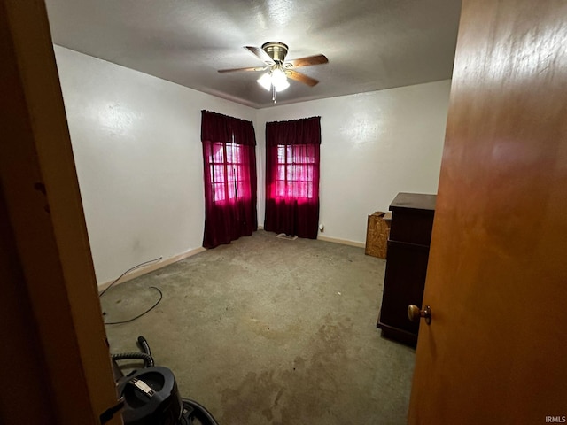 carpeted empty room with ceiling fan and baseboards