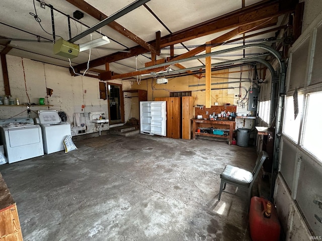 garage featuring a garage door opener, electric panel, independent washer and dryer, and a workshop area