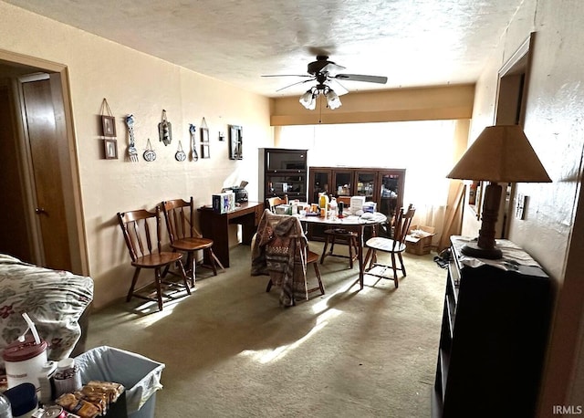 carpeted dining area with a textured ceiling, a textured wall, and a ceiling fan