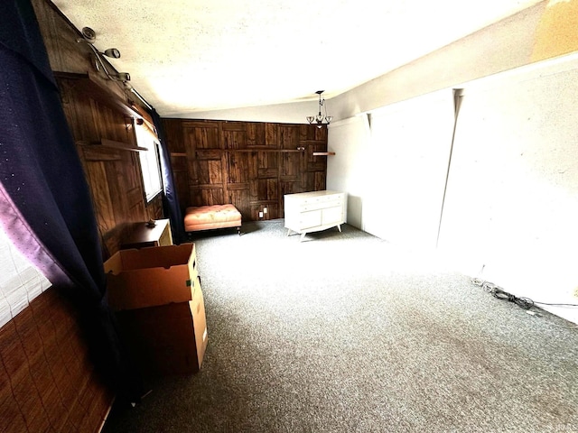 carpeted bedroom with wood walls, vaulted ceiling, and a textured ceiling