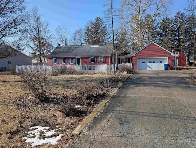 view of front of property with driveway, a chimney, a garage, and fence