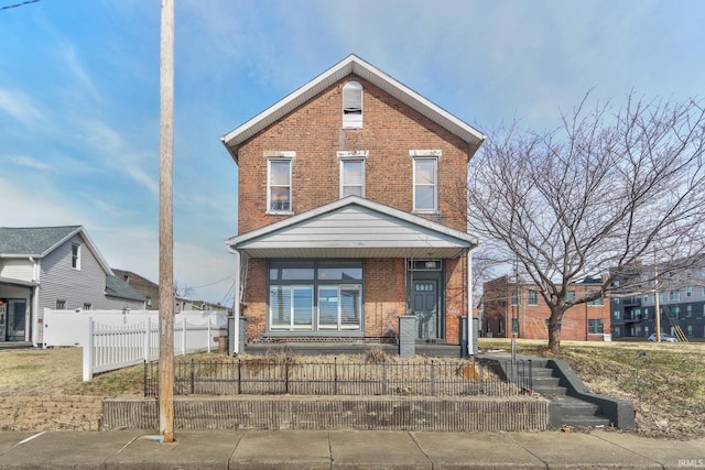 view of front facade with a fenced front yard, a porch, and brick siding