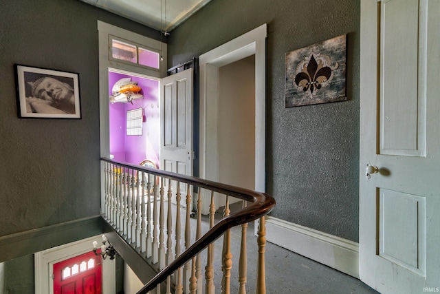 corridor with an upstairs landing, baseboards, and a textured wall