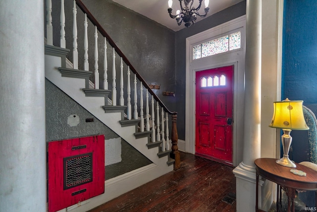 foyer featuring a notable chandelier, dark wood finished floors, a textured wall, baseboards, and stairs