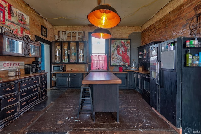 kitchen with glass insert cabinets, a center island, black refrigerator with ice dispenser, wooden counters, and a sink