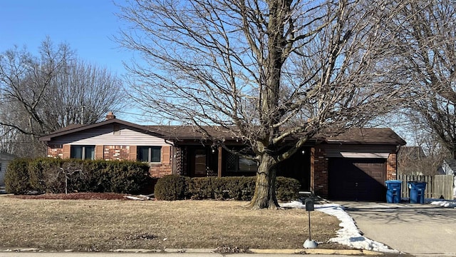 ranch-style home featuring a front lawn, concrete driveway, brick siding, and an attached garage