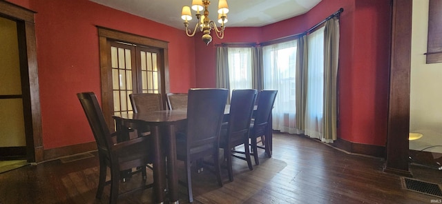 dining area with dark wood-style floors, baseboards, visible vents, and a chandelier