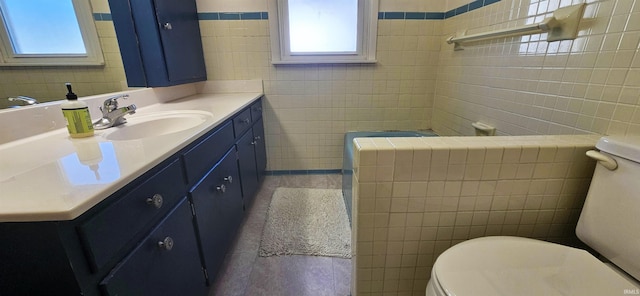 bathroom featuring toilet, tile walls, and vanity