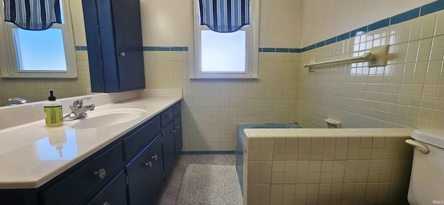 bathroom with toilet, a wainscoted wall, tile walls, and vanity