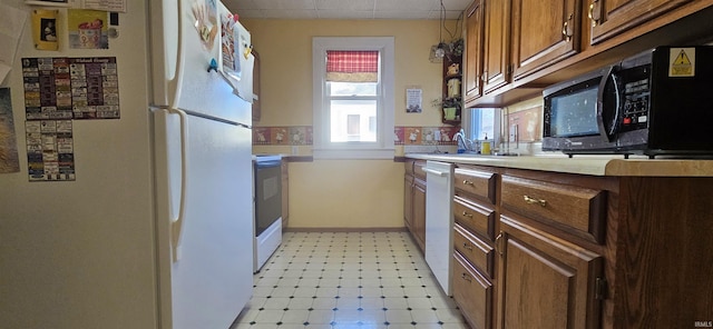 kitchen with white appliances, baseboards, light countertops, a paneled ceiling, and light floors