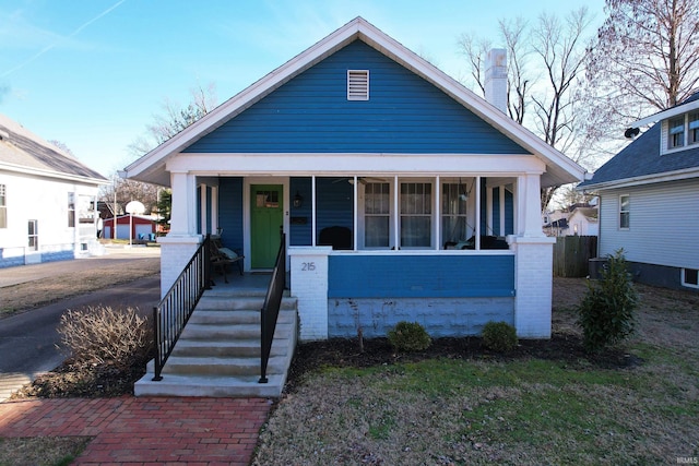 bungalow with a porch, central AC unit, and brick siding