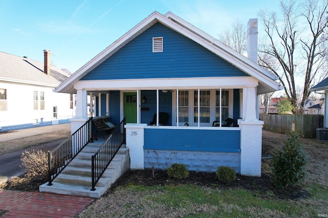 bungalow featuring covered porch, a chimney, and fence