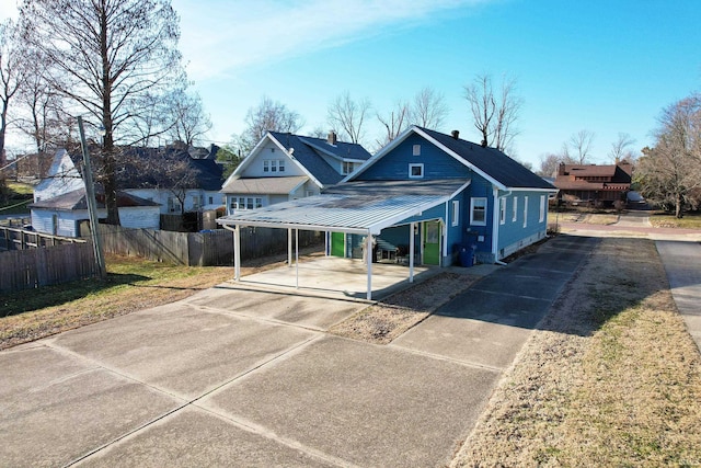 bungalow-style house featuring metal roof, fence, a residential view, a detached carport, and a standing seam roof