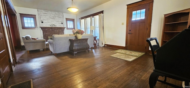 entryway with dark wood-type flooring, a fireplace, visible vents, and baseboards