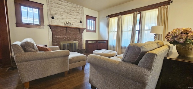 living room featuring visible vents, a brick fireplace, dark wood finished floors, and a wealth of natural light