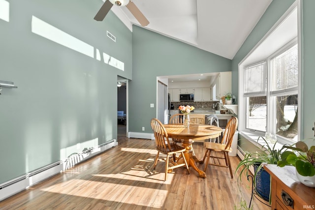 dining space with a baseboard heating unit, light wood-style flooring, visible vents, and ceiling fan