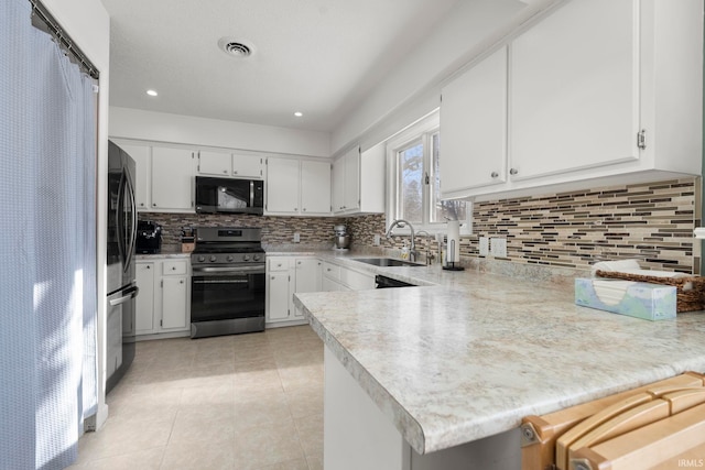 kitchen with stainless steel appliances, a peninsula, a sink, white cabinets, and light countertops